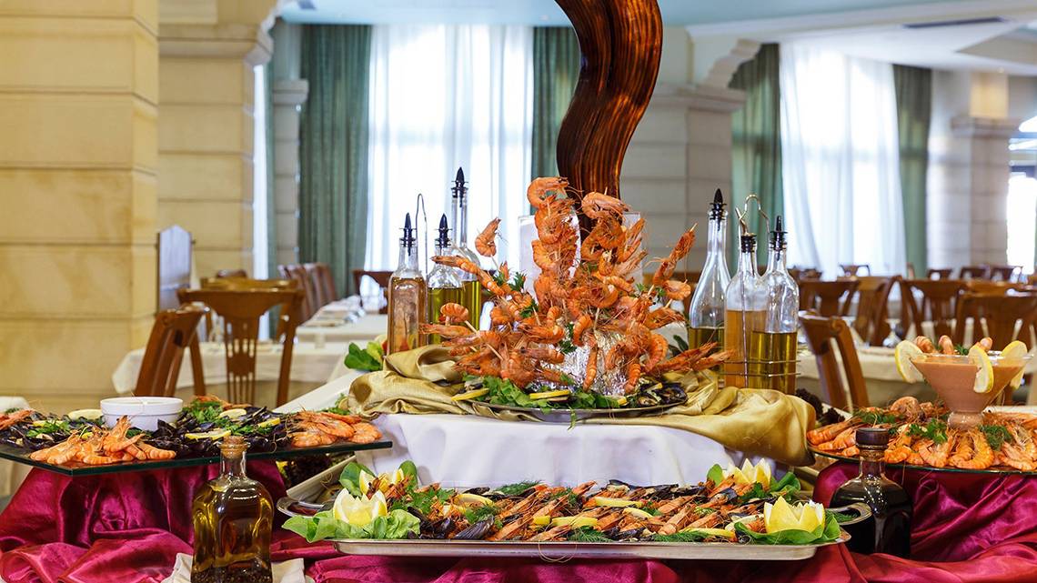 Buffet-Tisch im Lindos Princess Beach Hotel mit verschiedenen Meeresfrüchten und Olivenölflaschen.