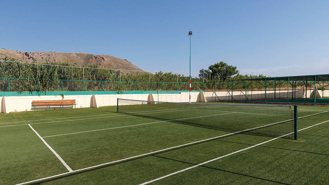 Tennisplatz des Lindos Princess Beach Hotels, umgeben von grünen Zäunen und einer Bank.