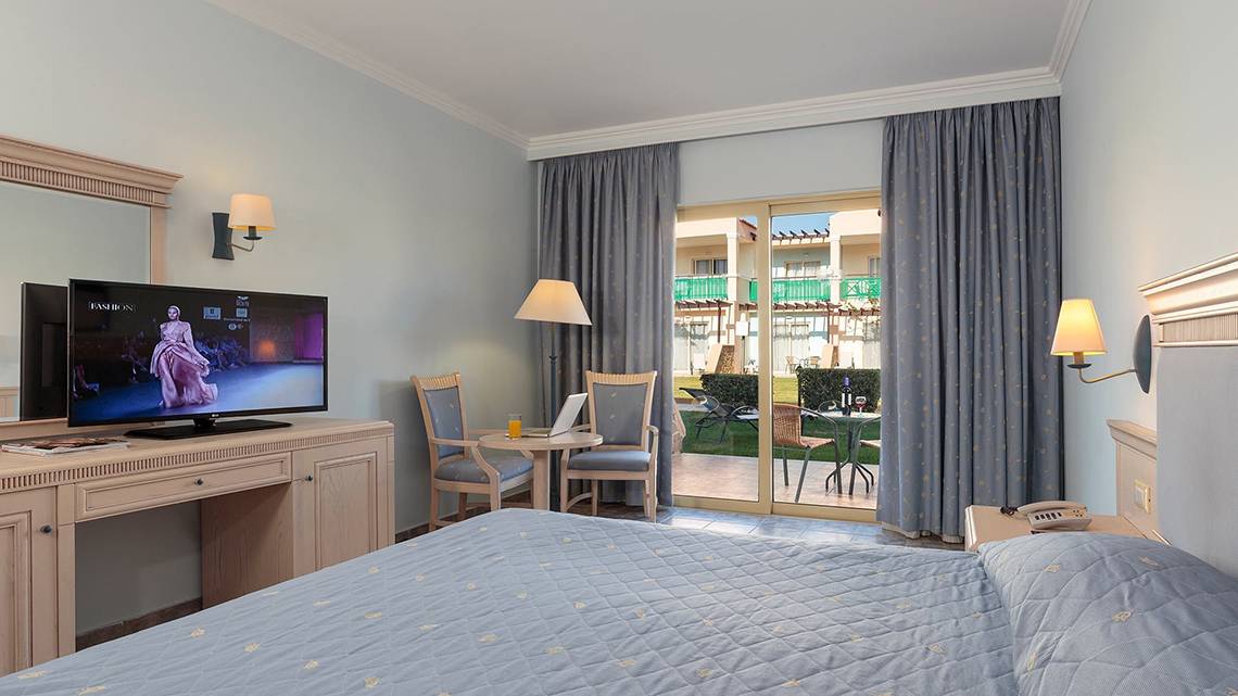 Hotelzimmer im Lindos Princess Beach mit Fernseher, Schreibtisch und Terrassenzugang.