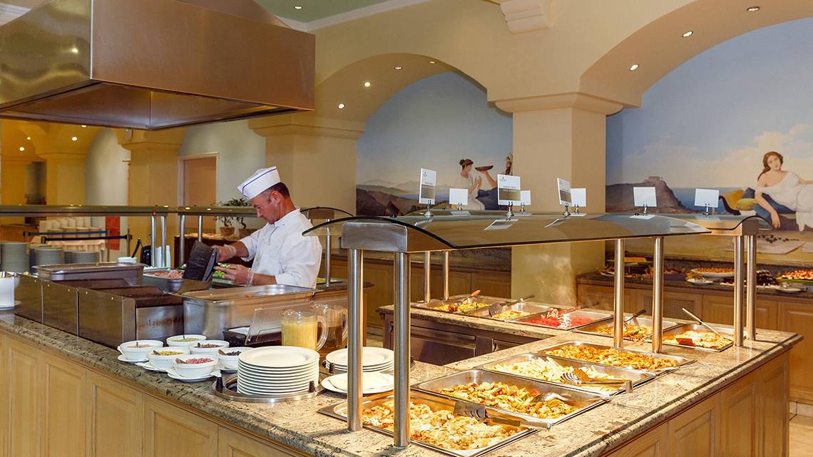 Buffet im Lindos Princess Beach Hotel mit einem Koch, der Essen zubereitet und serviert.