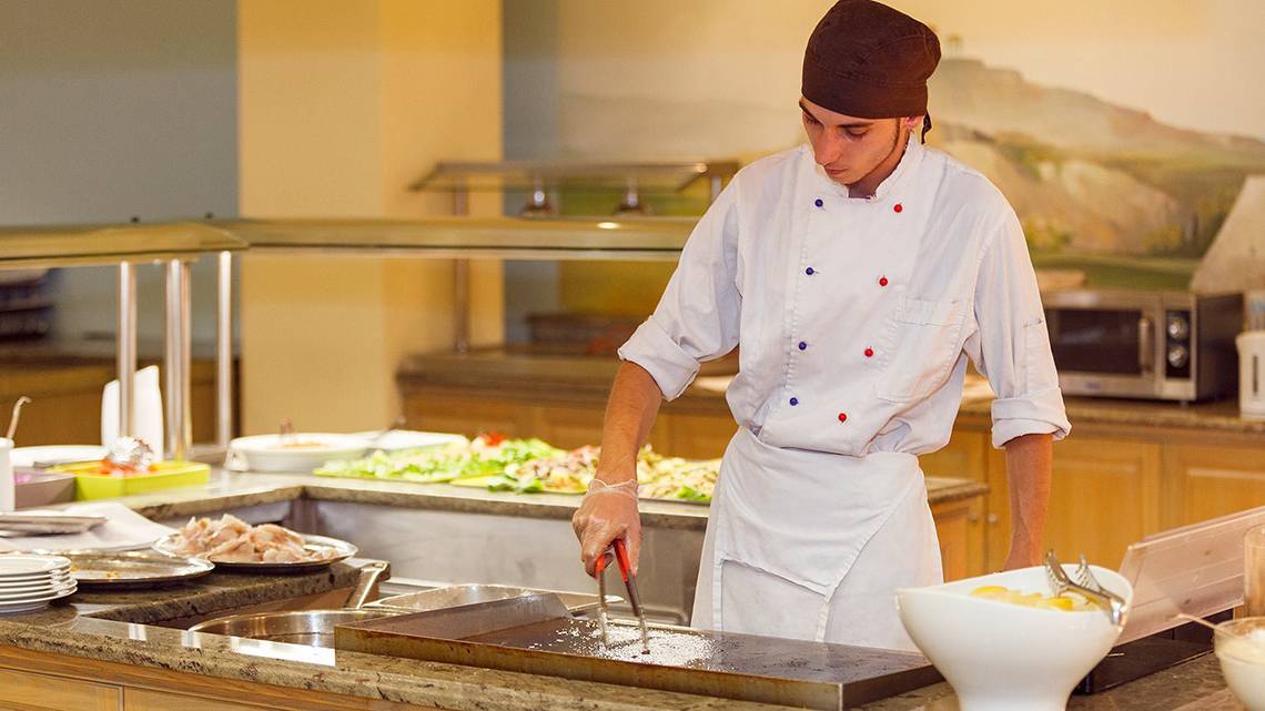 Koch im Hotel-Restaurant Lindos Princess Beach bereitet Essen auf einem Grill zu.