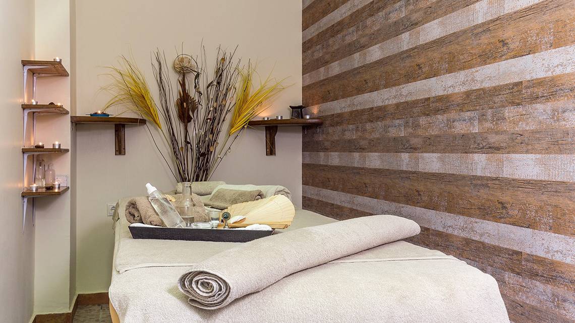 Spa-Behandlungsraum im Lindos Princess Beach Hotel mit Holzwand und Behandlungsliege.