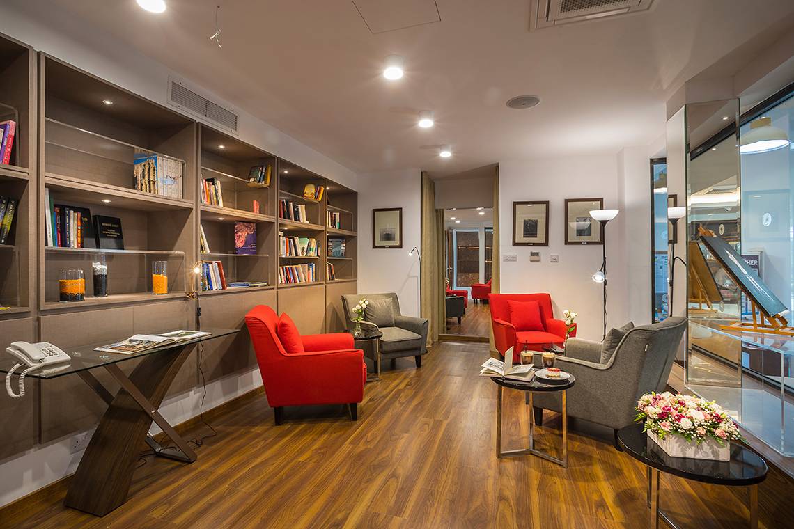 Innenansicht des Lordos Beach Hotels mit Bücherregal, roten Sesseln und Glastisch.