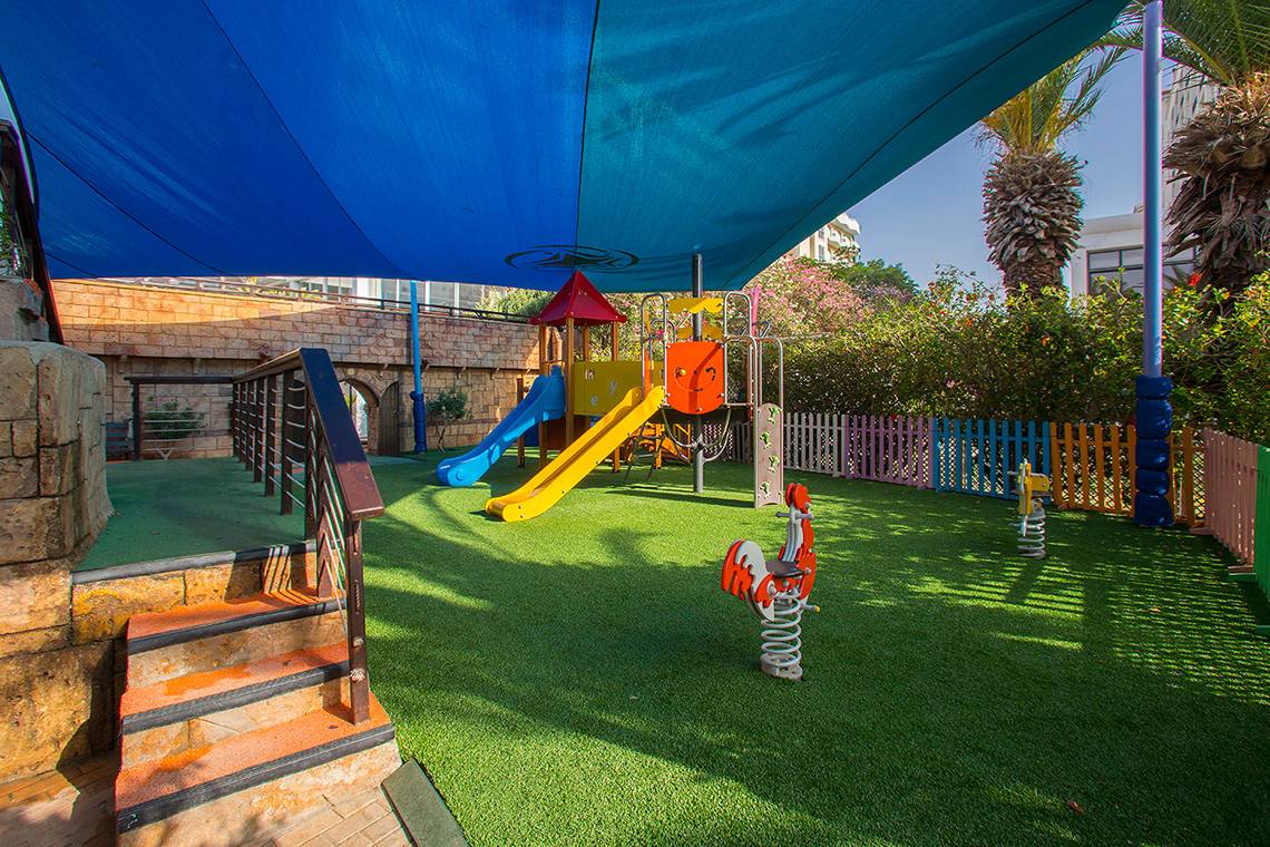 Kinderspielplatz im Lordos Beach Hotel mit Rutsche, Schaukel und Sandkasten.