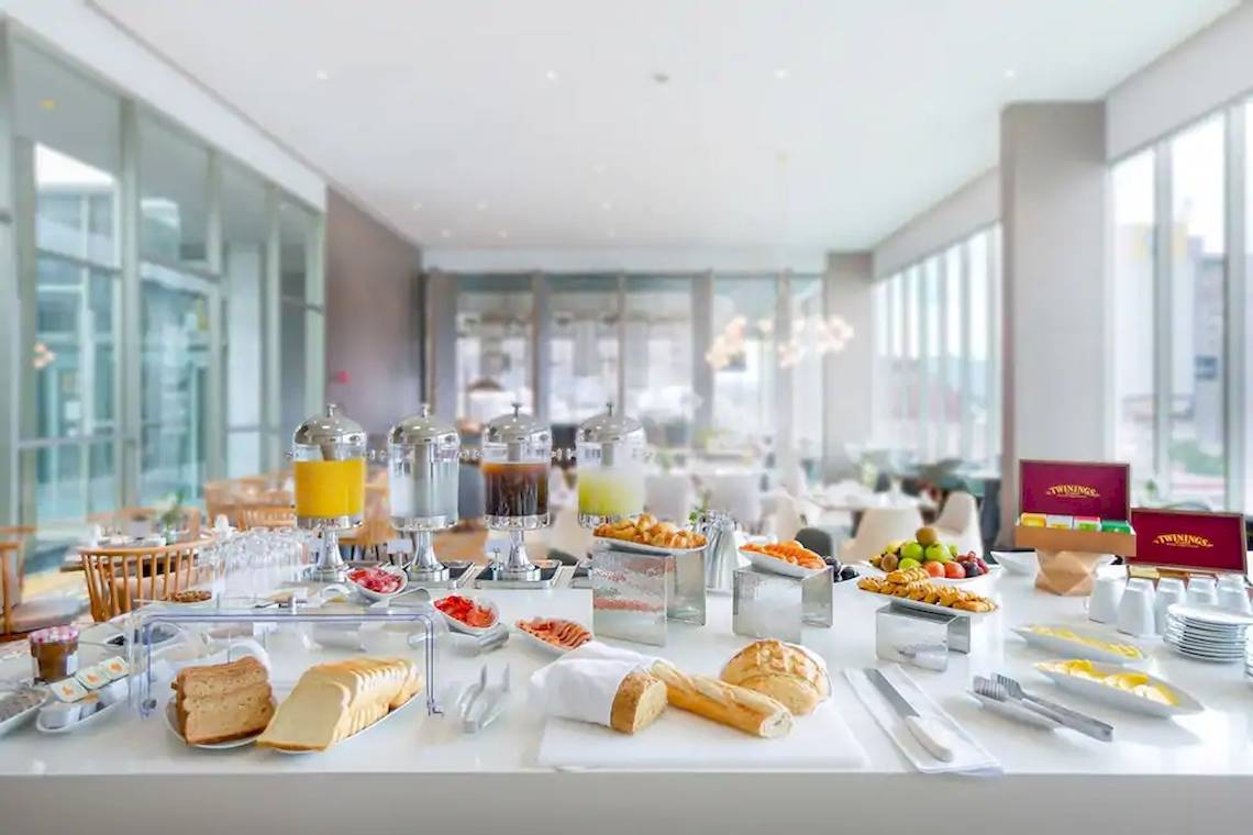 Frühstücksbuffet im Coco de Mer Hotel mit verschiedenen Brotsorten, Früchten und Getränken.
