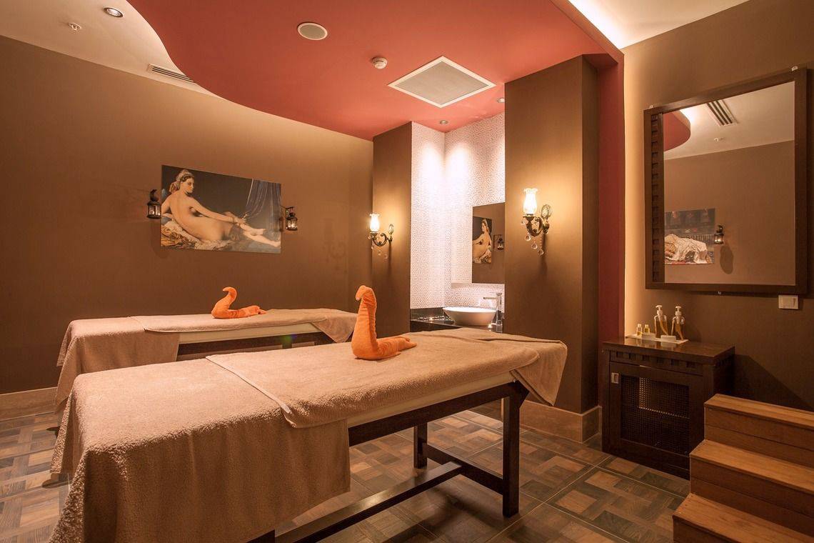 Massageraum im Side Orange Palace Hotel mit zwei Massagetischen, Kerzen und einem Spiegel.