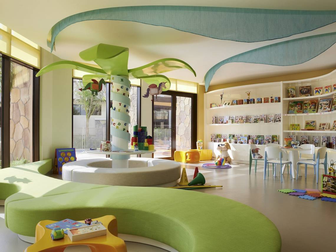 Kinderzimmer im Sofitel Dubai The Palm mit grünen Möbeln, Bücherregalen und Spielsachen.