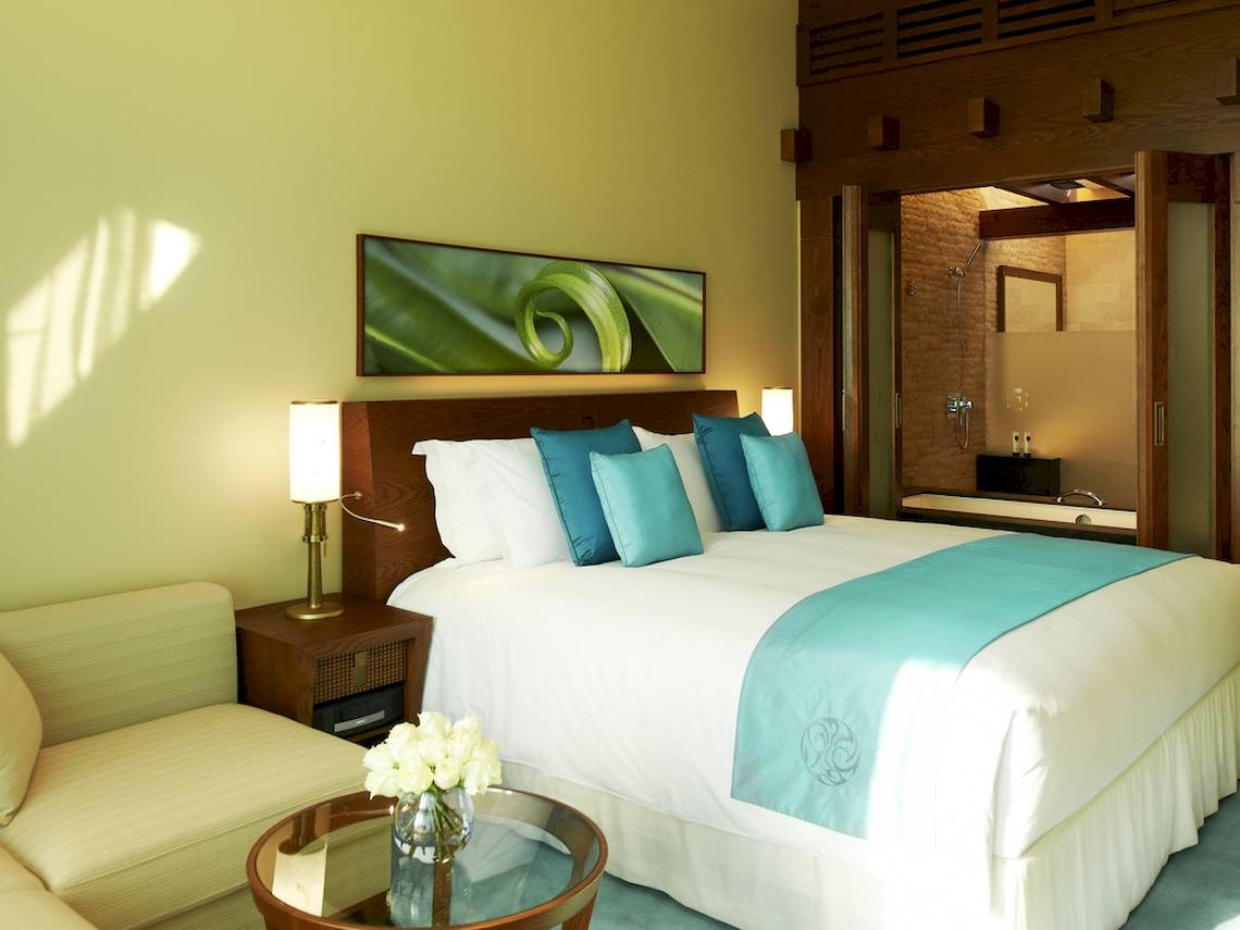 Schlafzimmer im Sofitel Dubai The Palm mit blauen Kissen und einem großen Bett.