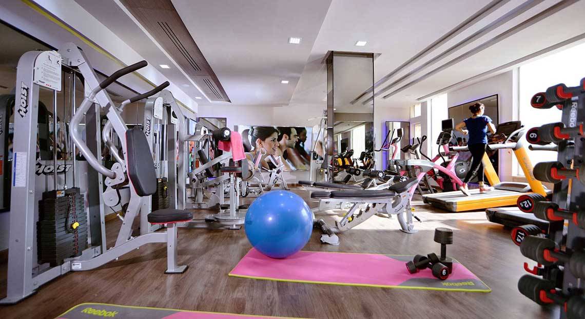 Fitnessstudio im Pickalbatros White Beach Resort mit verschiedenen Geräten und einer Person, die auf einem Laufband läuft.