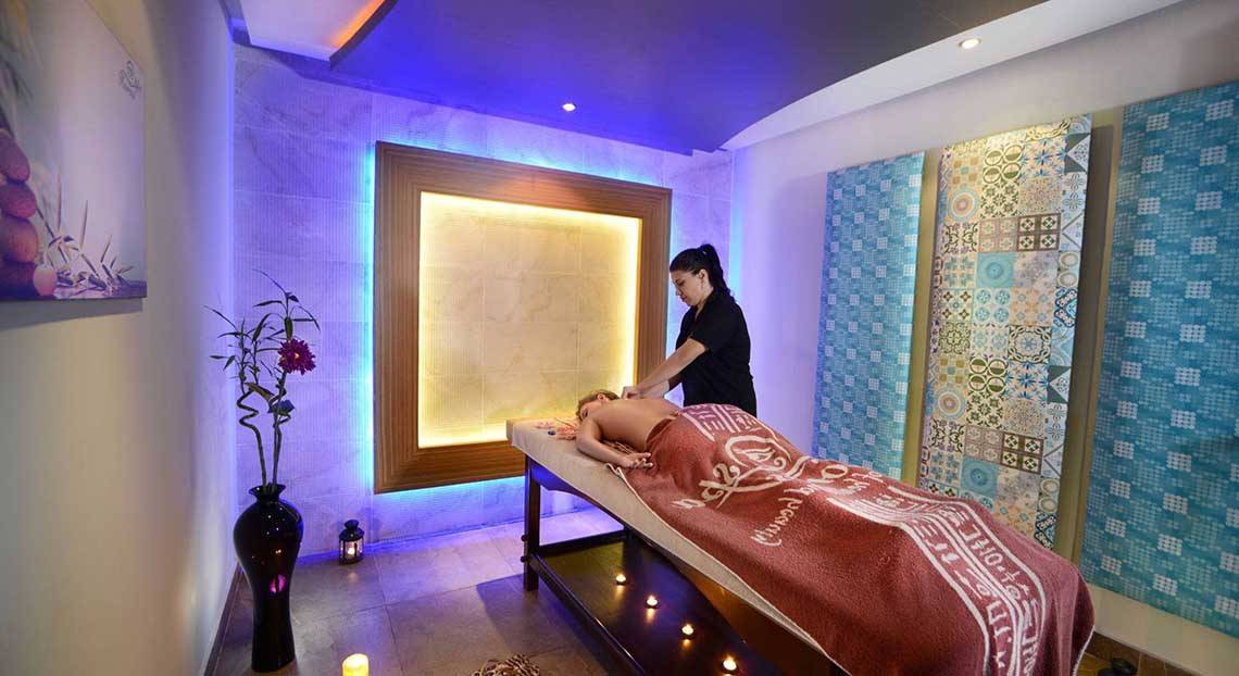 Eine Frau im schwarzen T-Shirt führt eine Massage in einem Hotelbehandlungsraum durch.