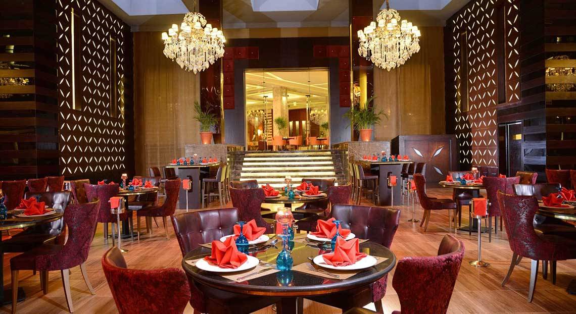 Innenansicht des Restaurants im Pickalbatros White Beach Resort mit geräumigen Tischen, luxuriösen Stühlen und großen Kronleuchtern.
