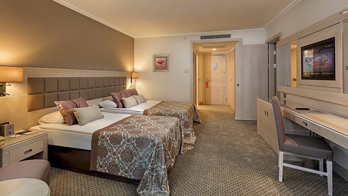 Doppelzimmer im Miracle Resort mit zwei Betten, Dekor, Fernseher, Schreibtisch und moderner Einrichtung.