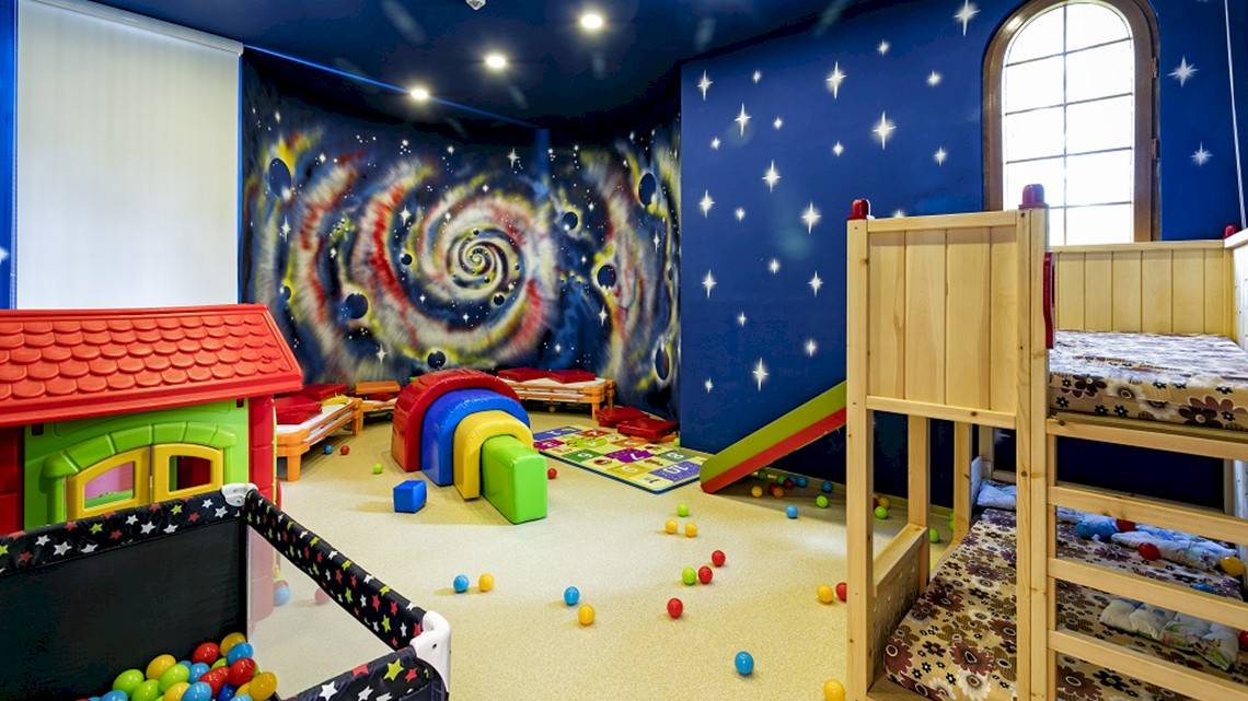 Kinderzimmer im Miracle Resort mit Galaxie-Thema, bunten Spielzeugen und Spielhaus.