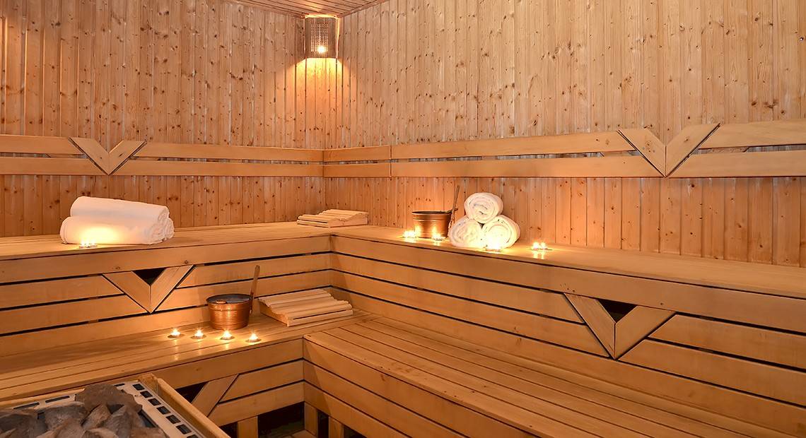 Sauna im Miracle Resort mit Holzbänken, Kerzen und Handtüchern.