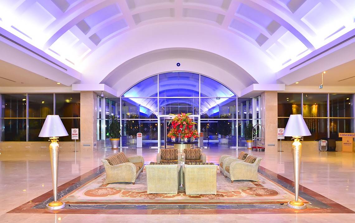 Ein Hotel-Foyer mit einem Blumenarrangement auf einem Tisch und umgeben von gepolsterten Sesseln.