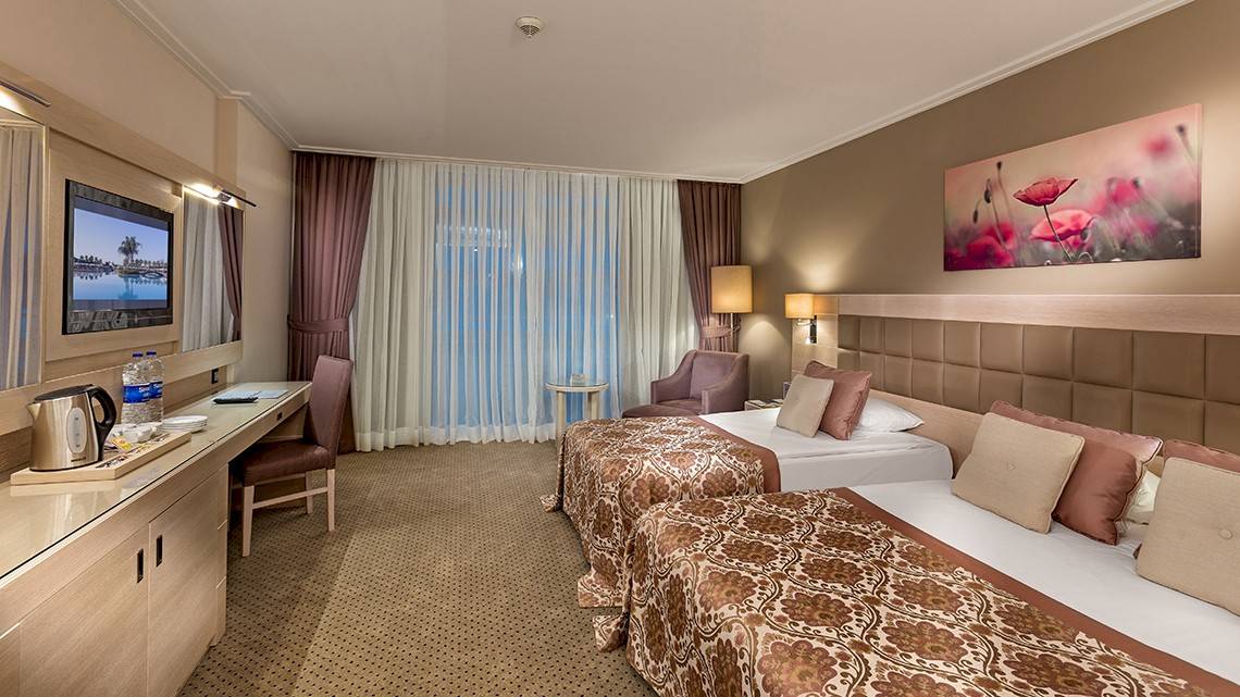 Doppelzimmer im Miracle Resort mit zwei Betten, Schreibtisch, Fernseher und Fenstern mit Blick auf den See.