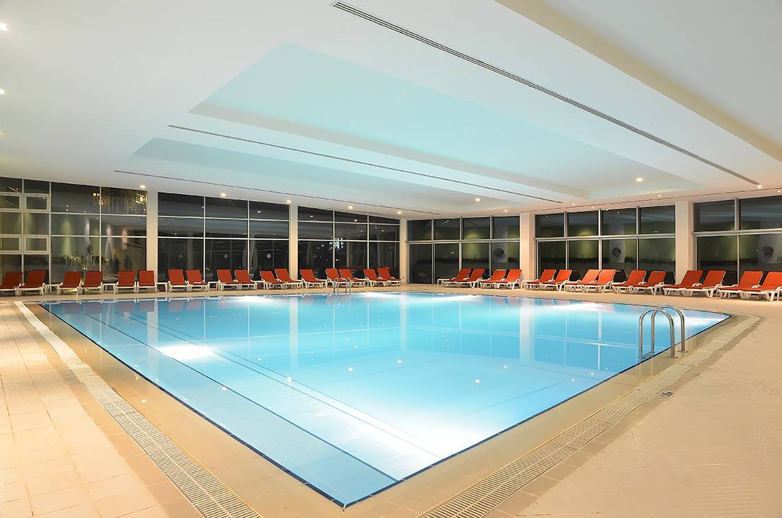 Wunderschöner Innenpool im Miracle Resort mit vielen roten Liegestühlen darum herum.