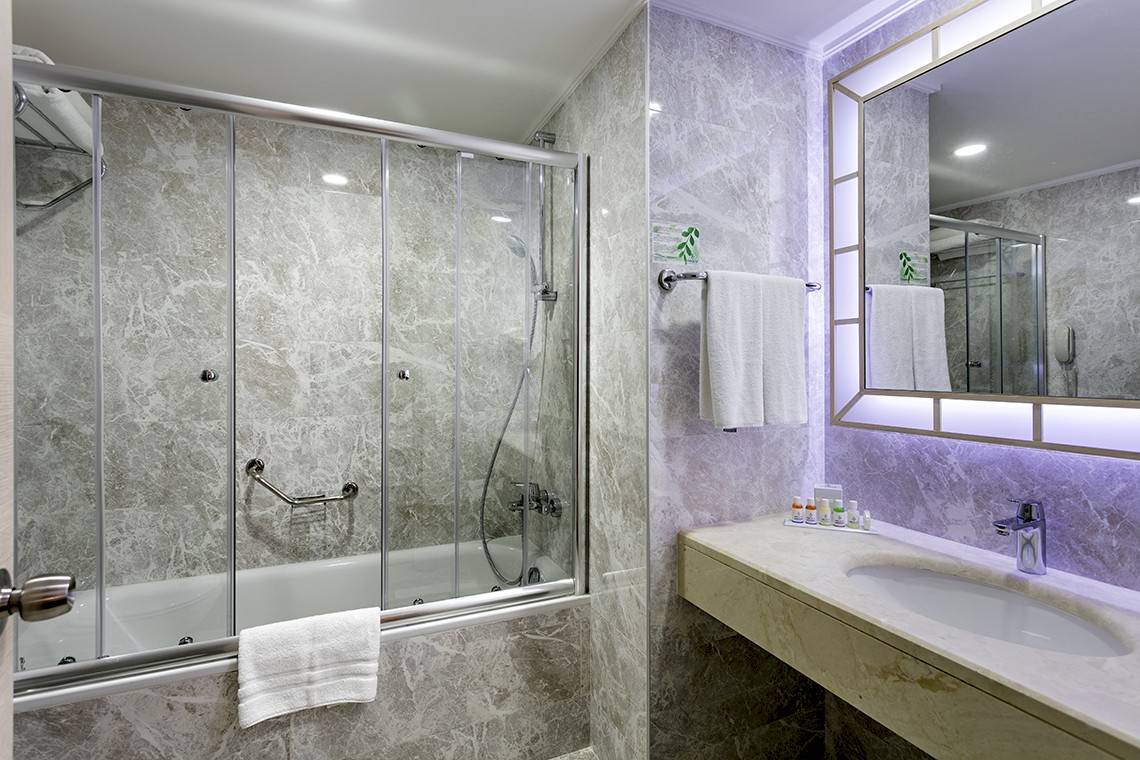 Badezimmer im Miracle Resort mit Badewanne, Dusche und Waschbecken.