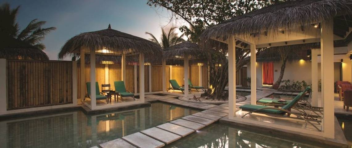 Außenbereich des Oblu Nature Hengeli mit Swimmingpool und Lounge-Gebieten unter Strohdächern.