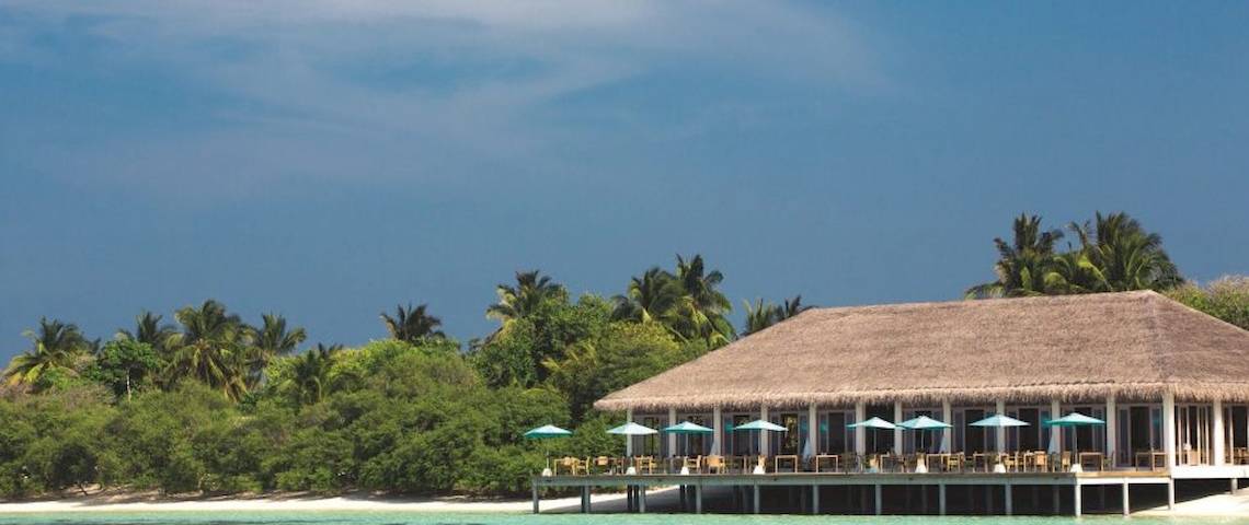 Außenbereich des Oblu Nature Hengeli Resorts mit vielen Tischen und Stühlen unter Sonnenschirmen.
