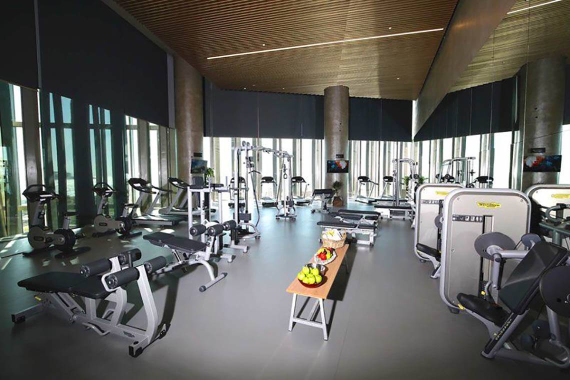 Fitnessstudio im Rixos Premium Dubai JBR mit verschiedenen Trainingsgeräten und einer Tafel mit Früchten.