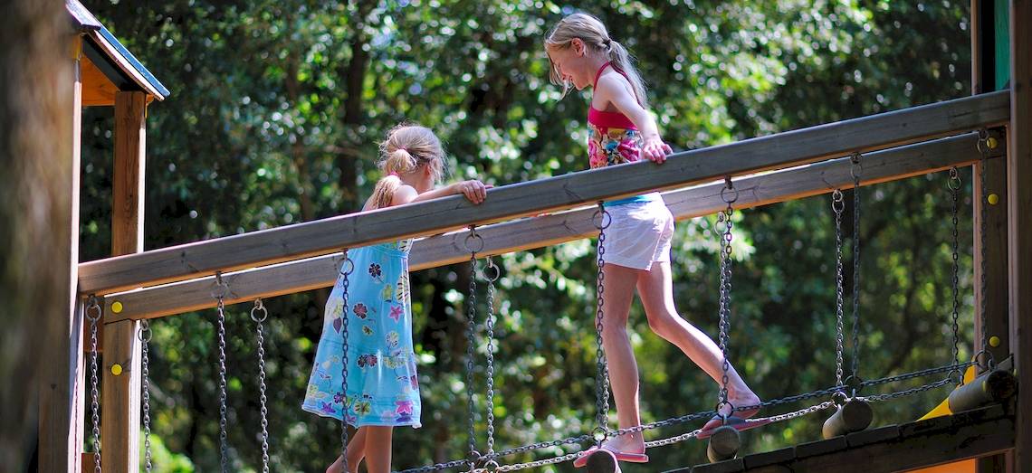 Zwei Maedchen auf einer Holz-Haengebruecke im Freizeitpark