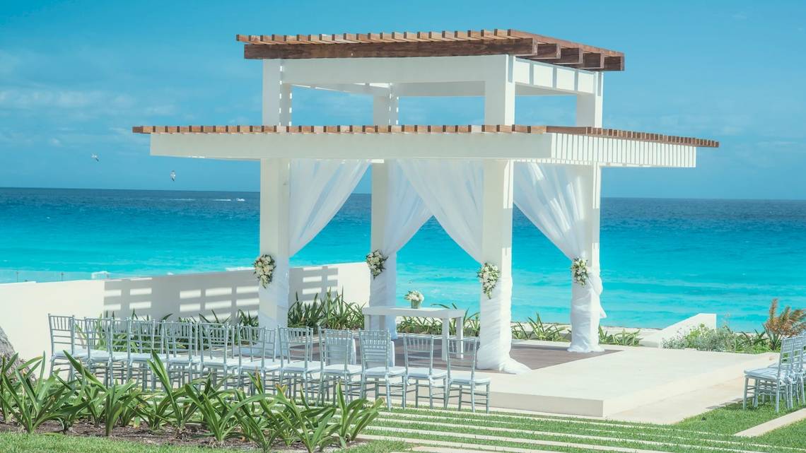 Strandzeremonie am Coral Level im Iberostar Selection Cancun mit weißem Pavillon und Blick auf das Meer.