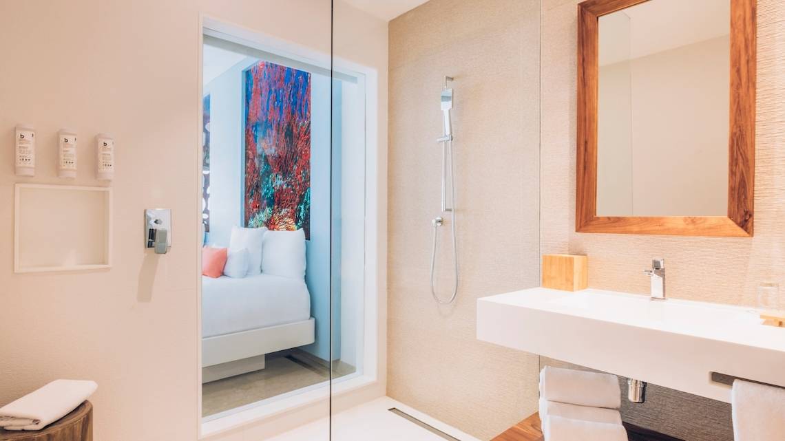 Badezimmer im Coral Level at Iberostar Selection Cancun Hotel mit Glasdusche und offenem Bett