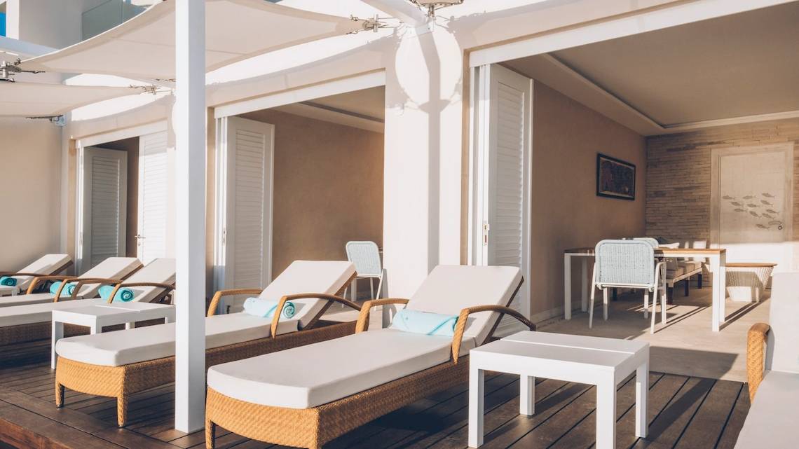 Loungebereich im Coral Level at Iberostar Selection Cancun mit weißen Liegestühlen und Tischen.