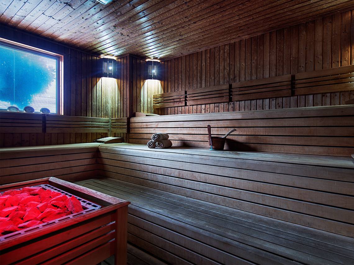 Eine leere Sauna mit Holzbänken und einem roten Feuerkorb im Crystal Family Resort & Spa.