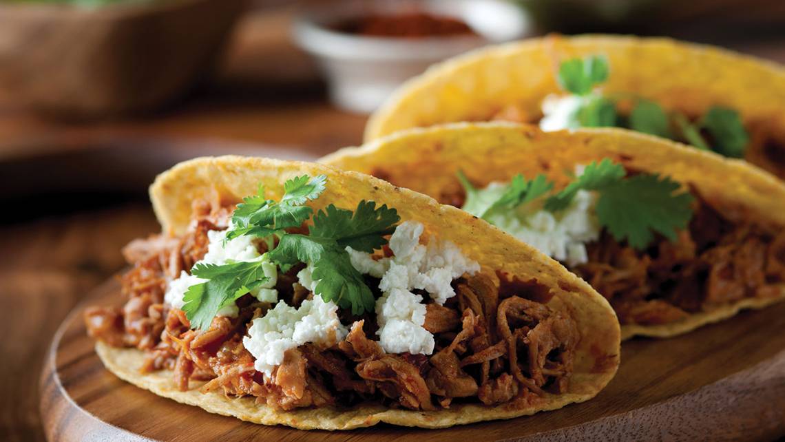 Ein Taco mit Rinderfleisch und Feta auf einer Holzplatte.