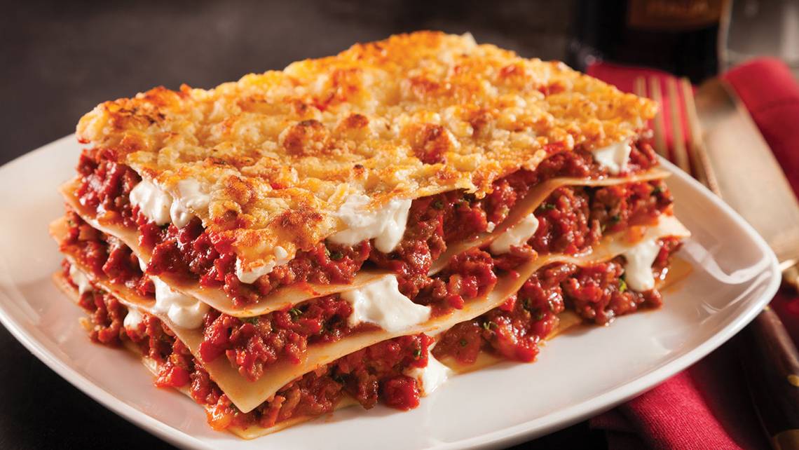 Eine Portion Lasagne mit Tomatensoße und Käse auf einem weißen Teller, serviert im Crystal Family Resort & Spa.