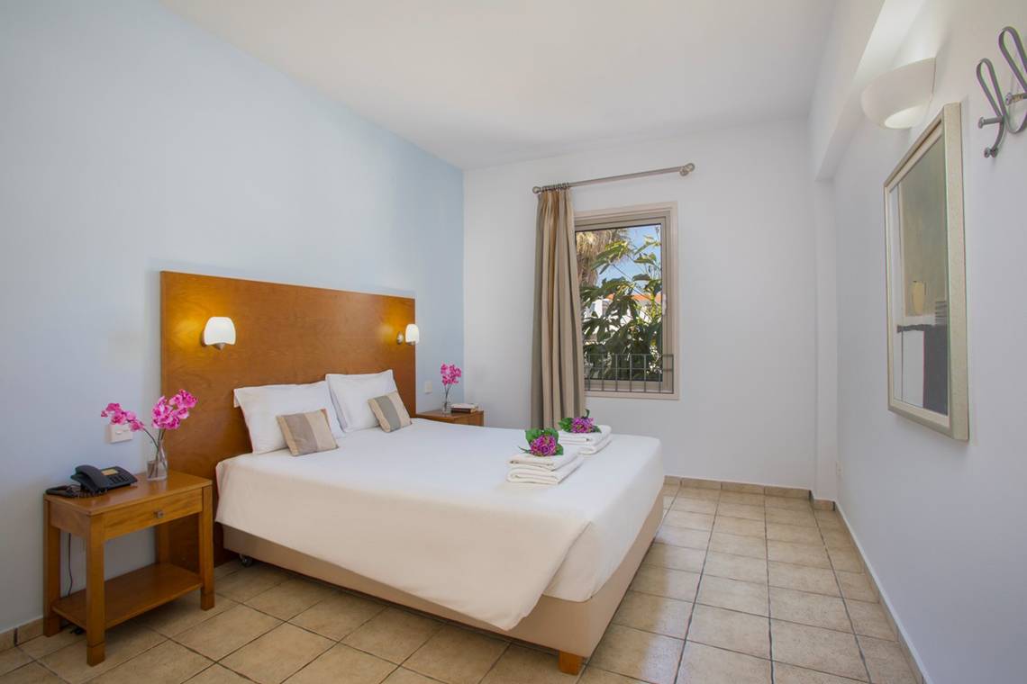 Ein modernes Hotelzimmer im Louis Althea Beach Hotel mit einem Doppelbett, Dekor und Blumen.