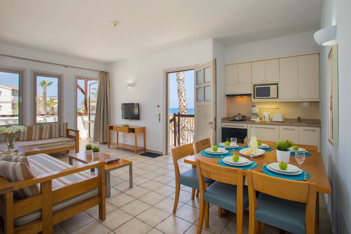 Wohnbereich des Louis Althea Beach Hotels mit Tisch und Stühlen, Blick auf den Ozean.