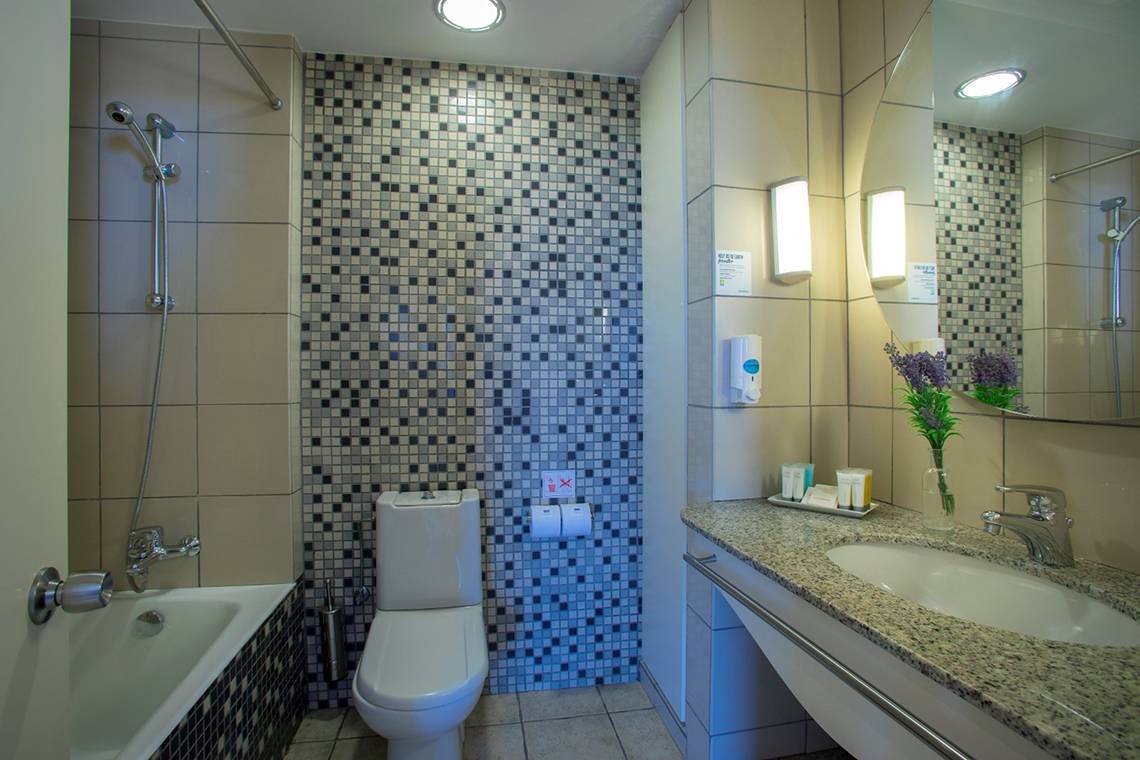 Badezimmer im Louis Althea Beach Hotel mit Badewanne, Toilette und Waschbecken.