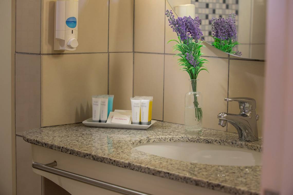 Badezimmer im Louis Althea Beach Hotel mit Waschbecken, Blumenvase und Handtüchern