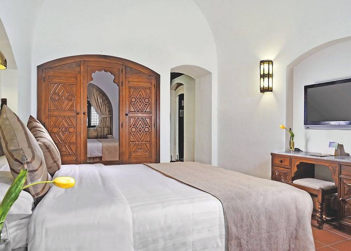 Schlafzimmer im Mövenpick Resort Sharm el Sheikh mit Doppelbett, Holzschrank und Fernseher