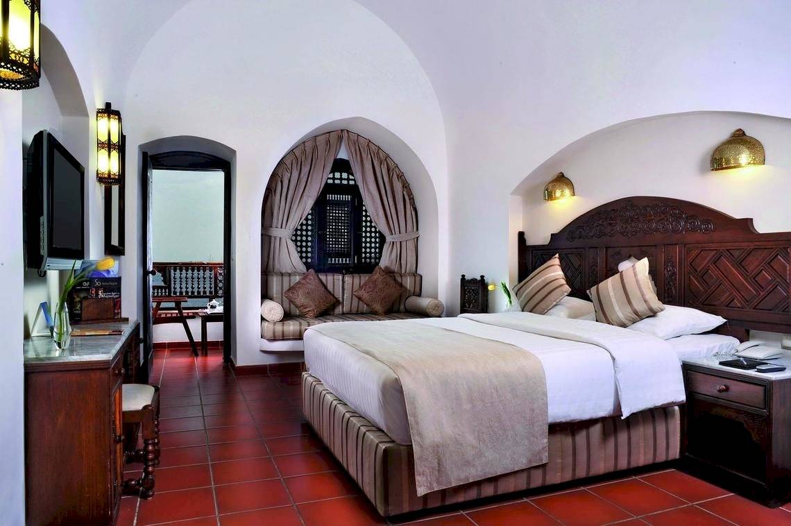 Schlafzimmer im Mövenpick Resort Sharm el Sheikh mit rotem Boden und traditionellem Bett.