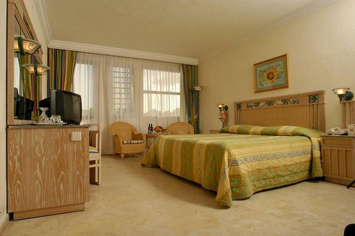 Hotelzimmer im Mövenpick Resort Sharm el Sheikh mit Doppelbett, Fernseher, Nachttischen und Fenstern.