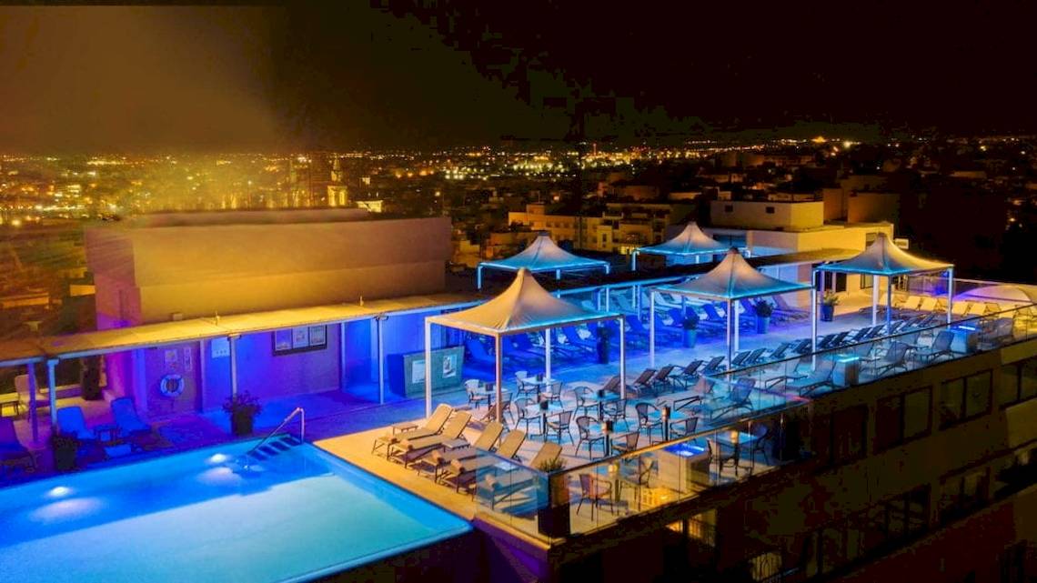 Nachtaufnahme der Dachterrasse des AX The Palace Hotels mit beleuchtetem Pool und Lounge-Bereichen