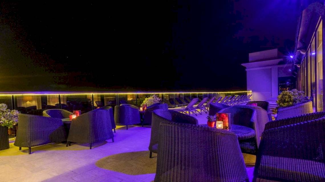 Terrasse des AX The Palace Hotels bei Nacht mit blauer Beleuchtung und gemütlichen Sitzgelegenheiten.
