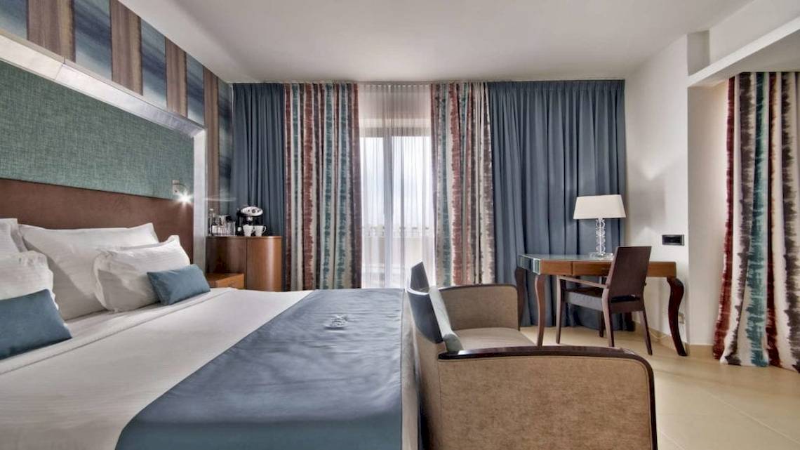 Suite-Zimmer im AX The Palace Hotel mit Bett, Schreibtisch und Sesseln.