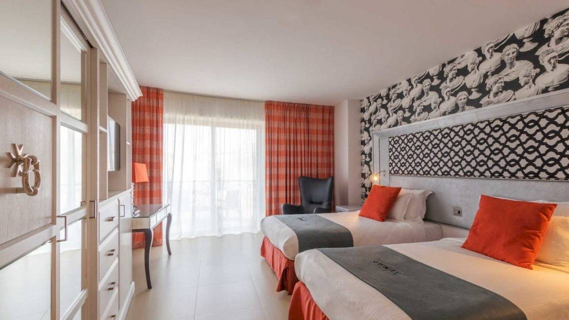 Doppelzimmer im AX The Palace Hotel mit zwei Betten, einem Schreibtisch, einem Stuhl und einem Fenster.