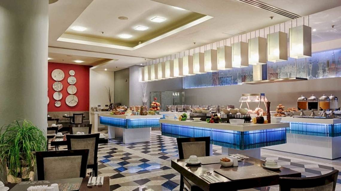 Innenansicht des Restaurants im AX The Palace Hotel mit Frühstücksbuffet, Tischen und Stühlen.