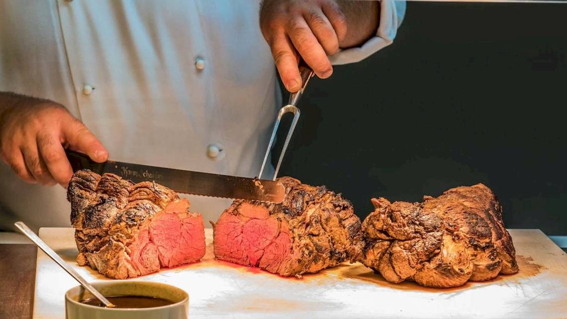 Koch im AX The Palace schneidet ein Steak mit einem Messer.