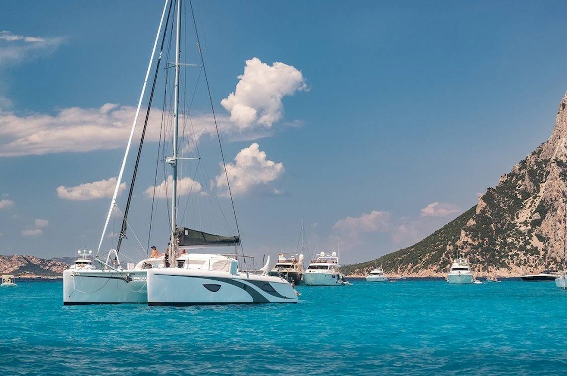 Hotel Ollastu Resort Boote im Wasser vor einer felsigen Küste