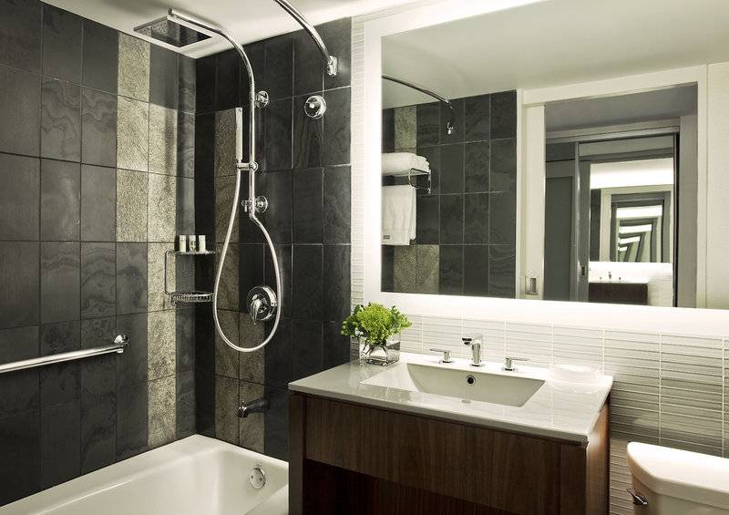 Badezimmer im Westin New York at Times Square Hotel mit Badewanne, Dusche, Waschbecken und Spiegel.