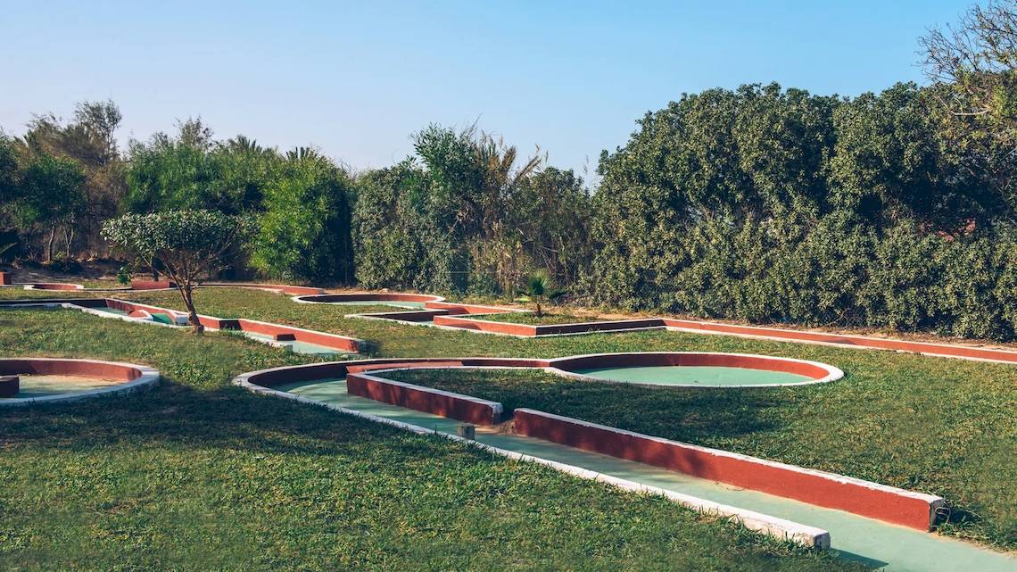 Golfplatz im Freien im Iberostar Mehari Djerba Hotel, umgeben von Bäumen und grünem Rasen.