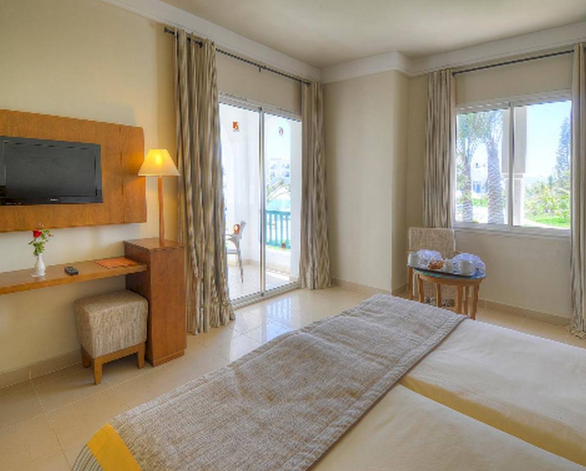 Doppelzimmer mit Balkon im Vincci Helios Beach Hotel, inklusive Fernseher, Schreibtisch, bequemen Betten und Blick auf den Garten.