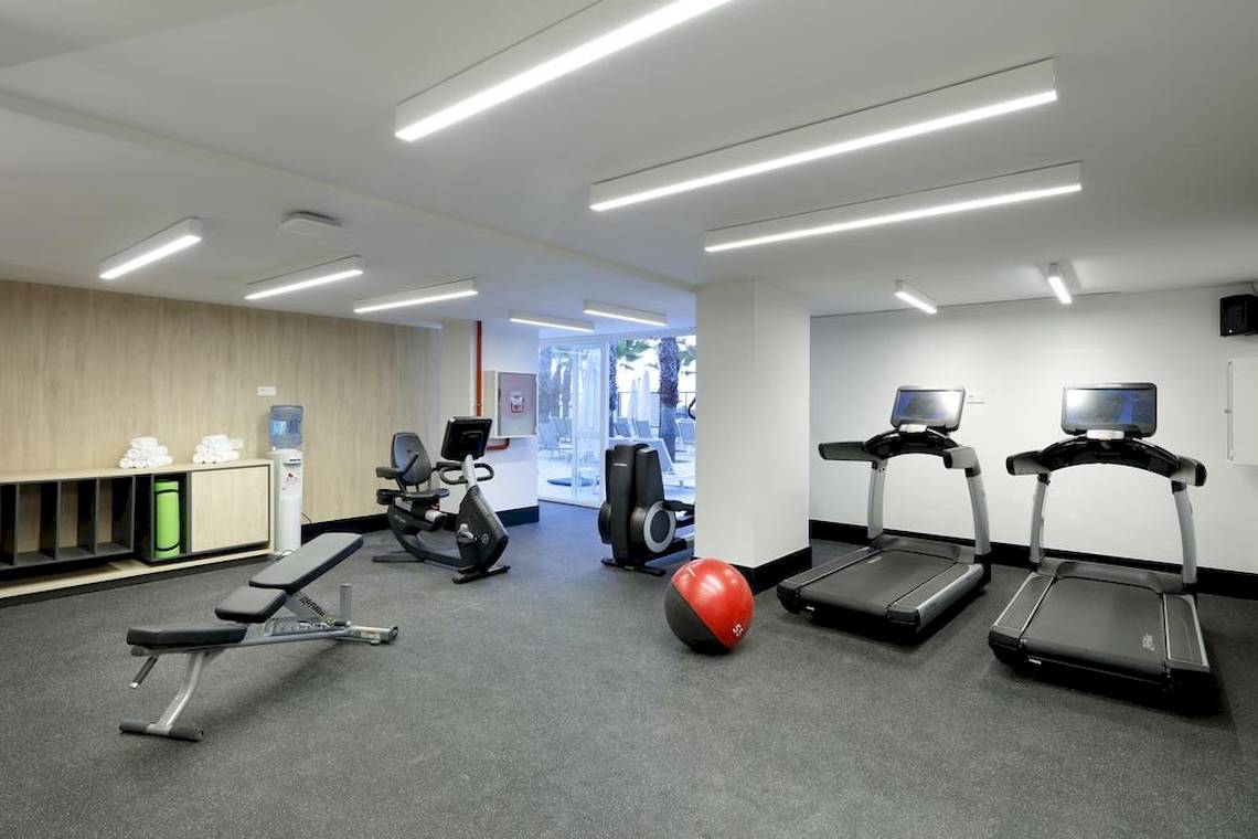 Fitnessraum im Playabonita Hotel mit Laufbändern, einer Bank und einem Medizinball.
